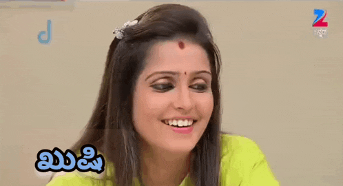 a woman with a red bindi on her forehead is smiling in a video .