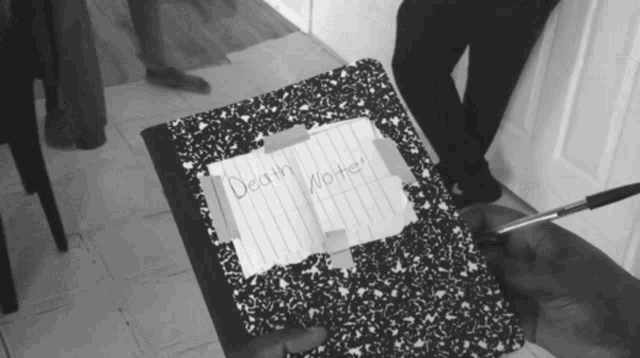 a notebook with a piece of paper taped to the top that says death wrote