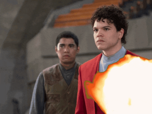 two men are standing next to each other and one of them has a fireball in his hand
