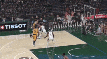 a basketball game is being played in front of a tissot advertisement
