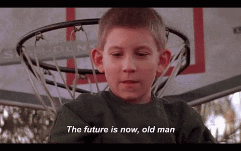 a young boy sitting in front of a basketball hoop says the future is now , old man