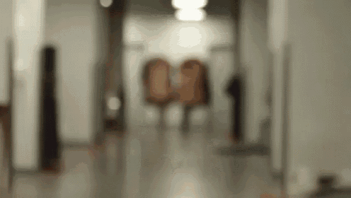 a blurred image of a hallway with a few people walking down it .