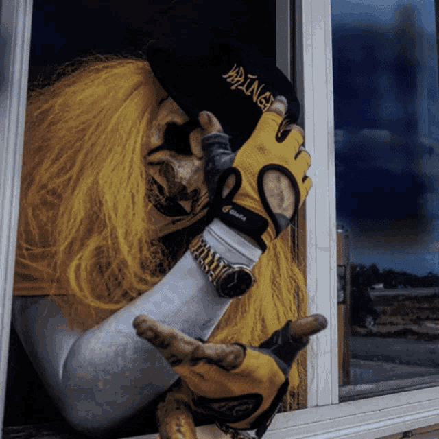 a person wearing yellow gloves and a watch holds a hat that says viking
