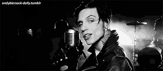 a man is singing into a microphone in a black and white photo .