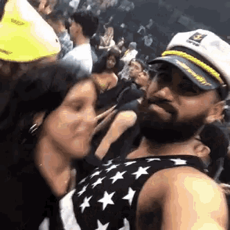 a man wearing a captain 's hat is kissing a woman in a crowd .