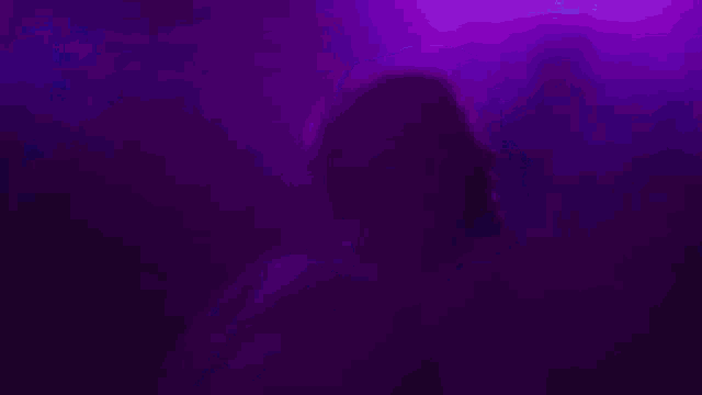 a silhouette of a person in a dark room with purple lights behind him .