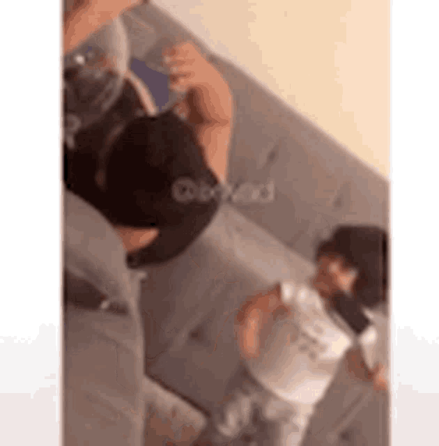 a man is laying on a couch with a baby and a little girl standing next to him .