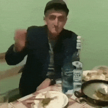 a man is sitting at a table with a bottle of silver water in front of him .