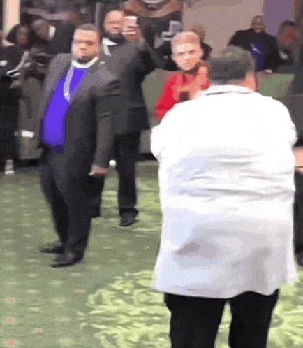 a man in a white coat is taking a picture of another man in a suit