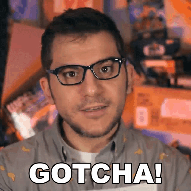 a man wearing glasses says gotcha in front of a blurry background