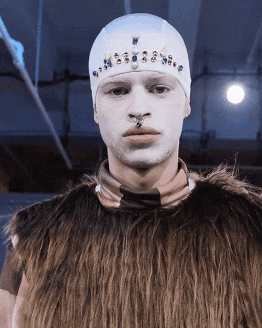 a man with white paint on his face and a fur coat