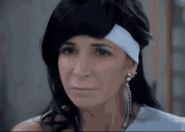 a close up of a woman wearing a wig and earrings .