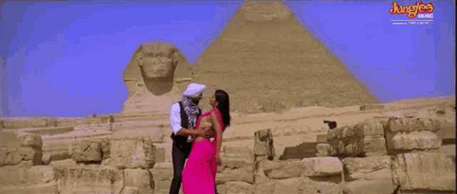 a man and woman are dancing in front of a pyramid with junglee music written on the bottom of the screen
