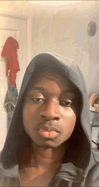 a man wearing a hooded sweatshirt looks at the camera