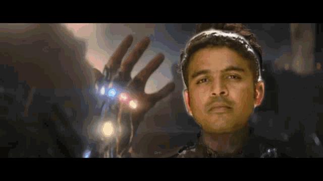 a man wearing a headband is holding up his hand with the infinity gauntlet