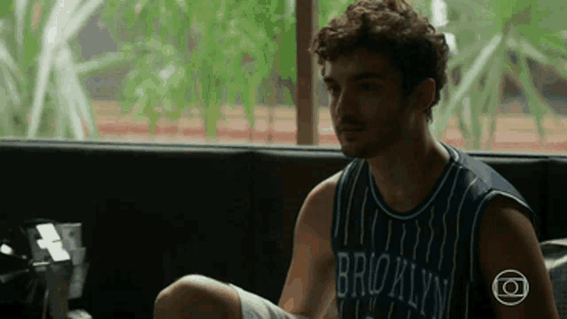 a man in a brooklyn jersey sits on a bench