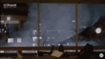 a blurry picture of a room with a large window and a city skyline in the background .