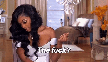 a woman in a white dress is sitting in a chair in a living room and says the fuck .