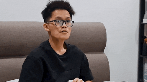a young man wearing glasses and a black shirt