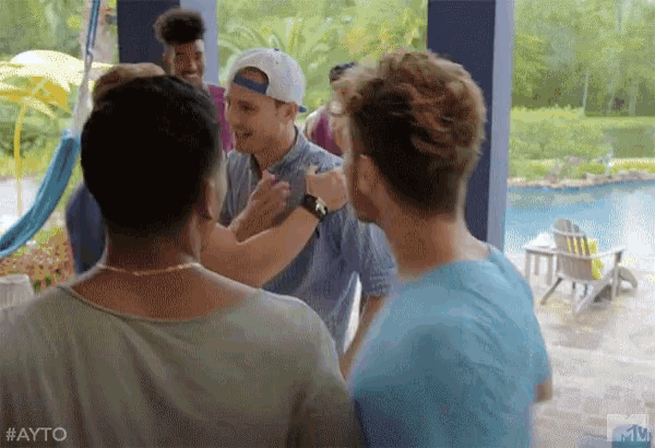 a group of people are standing in front of a pool and talking to each other .