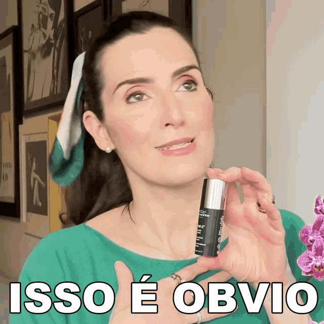 a woman in a green shirt holds a bottle of isso e obvio