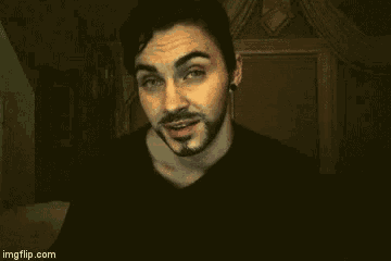 a man with a beard is smiling and looking at the camera while wearing a black shirt .