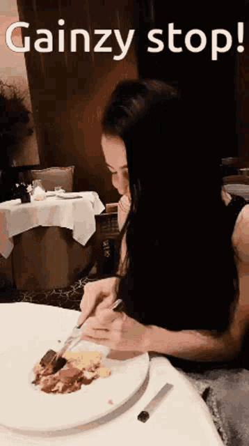 a woman sits at a table with a plate of food and the words gainzy stop
