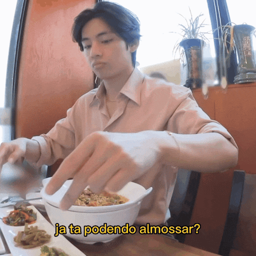 a man sitting at a table with a bowl of food and the words ja ta podendo almossar written above him