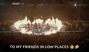 a group of people are standing in front of a stage with flames coming out of it and the words `` to my friends in low places ''
