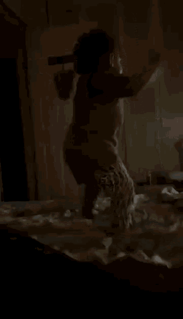a little girl is jumping on a bed in the dark