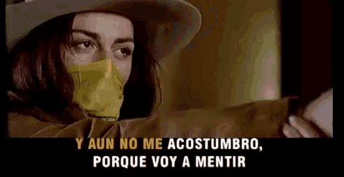 a woman wearing a cowboy hat and a yellow tape around her mouth is holding a gun .