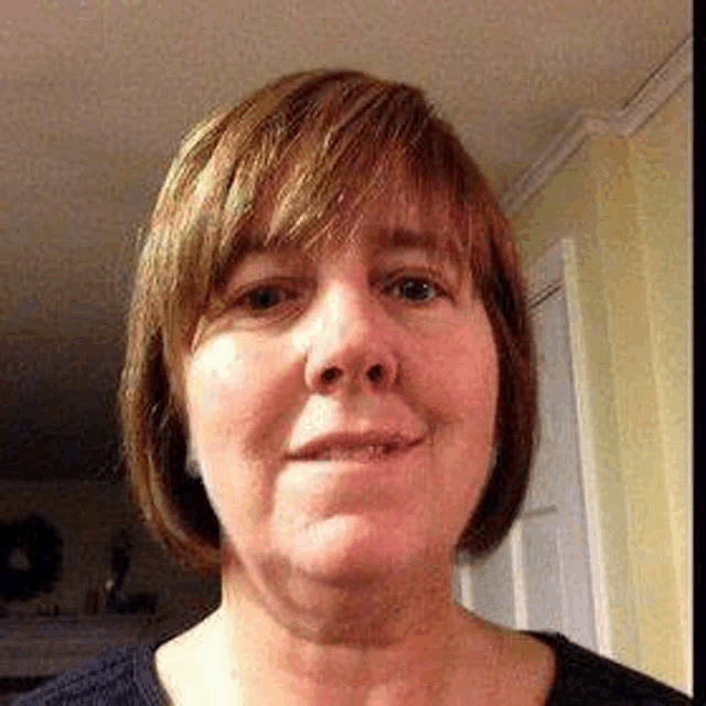 a close up of a woman 's face with short hair and a black shirt .