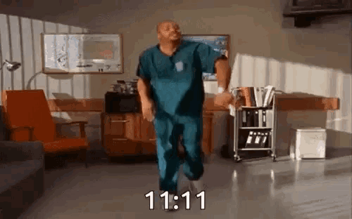 a man in scrubs is dancing in a hospital room with the time 11:11