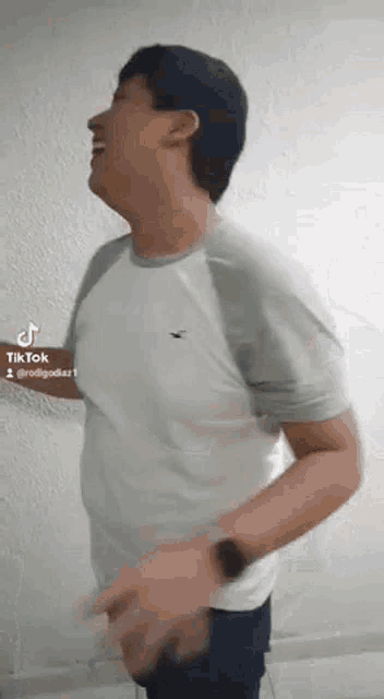 a man in a white shirt is standing in front of a white wall .