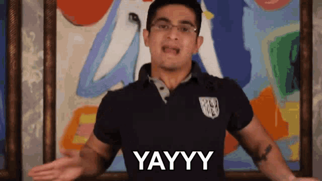 a man wearing a black shirt says yayy in front of a painting