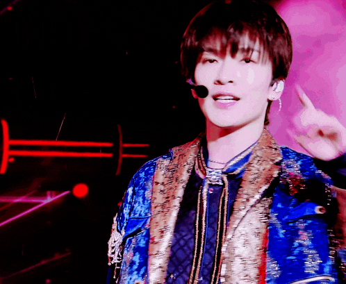 a man wearing a blue and gold jacket with a microphone pointing upwards