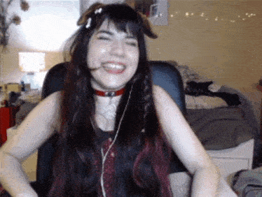 a woman wearing a choker and headphones is laughing while sitting in a chair