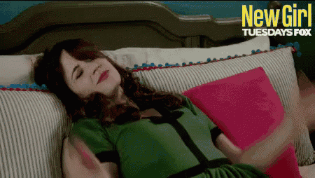 a woman in a green dress is laying on a bed with a pink pillow and a sign that says new girl
