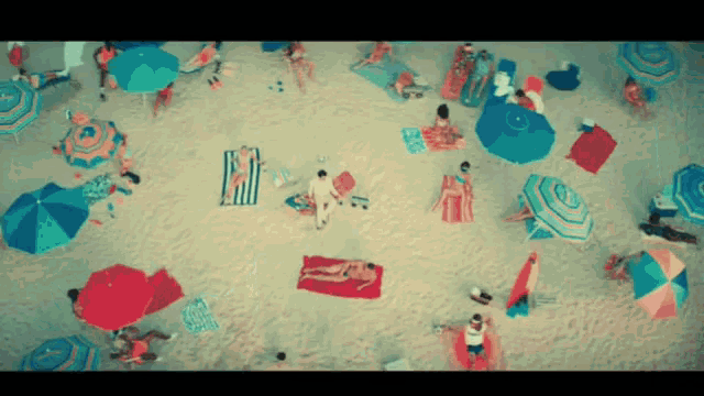 an aerial view of a beach filled with people umbrellas and towels