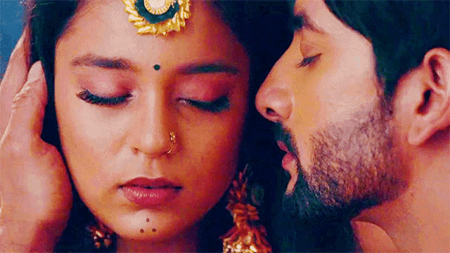 a close up of a man kissing a woman 's forehead