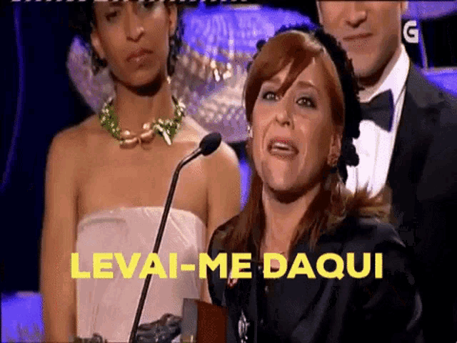 a woman crying in front of a microphone with the words levai-me daqui written in yellow