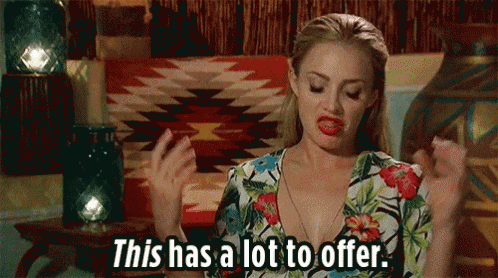 a woman in a floral dress is sitting on a couch and says this has a lot to offer .