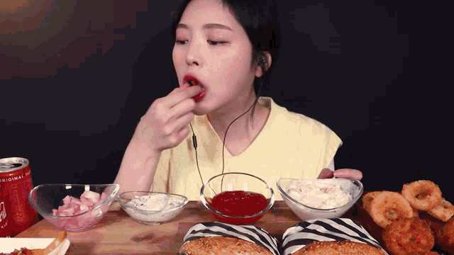 a woman is eating hamburgers and onion rings with a can of diet coke
