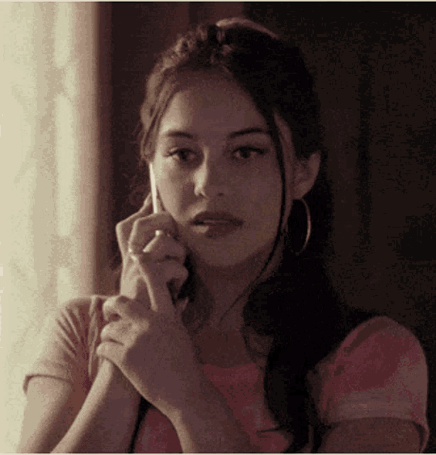 a woman in a pink shirt is talking on her phone