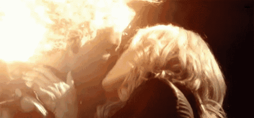 a woman is blowing fire from her mouth in a dark room .