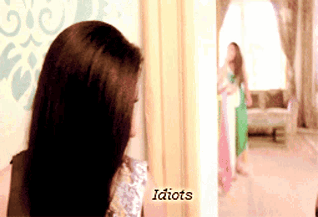 a woman stands in front of a mirror with the words idiots on the bottom right