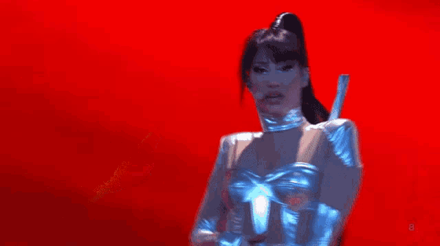 a woman in a futuristic outfit is standing on a stage with a microphone .