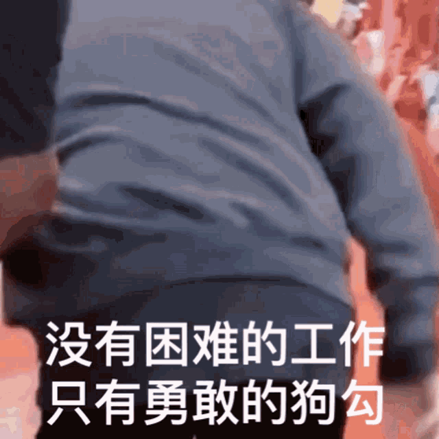 a man in a grey sweater is walking with chinese writing on the bottom