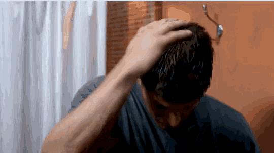 a man in a blue shirt holds his hand to his head