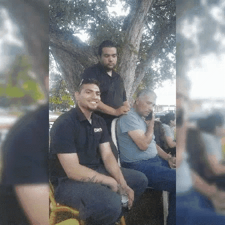 a group of men are sitting under a tree and one of them is wearing a shirt that says ' earl '